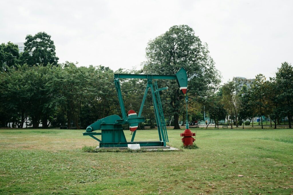 a green oil pump sitting in a field next to a red fire hydrant